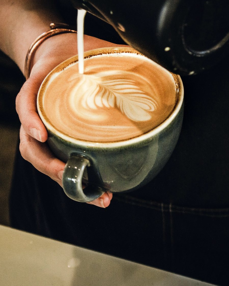 A barista pouring latte art into a cup