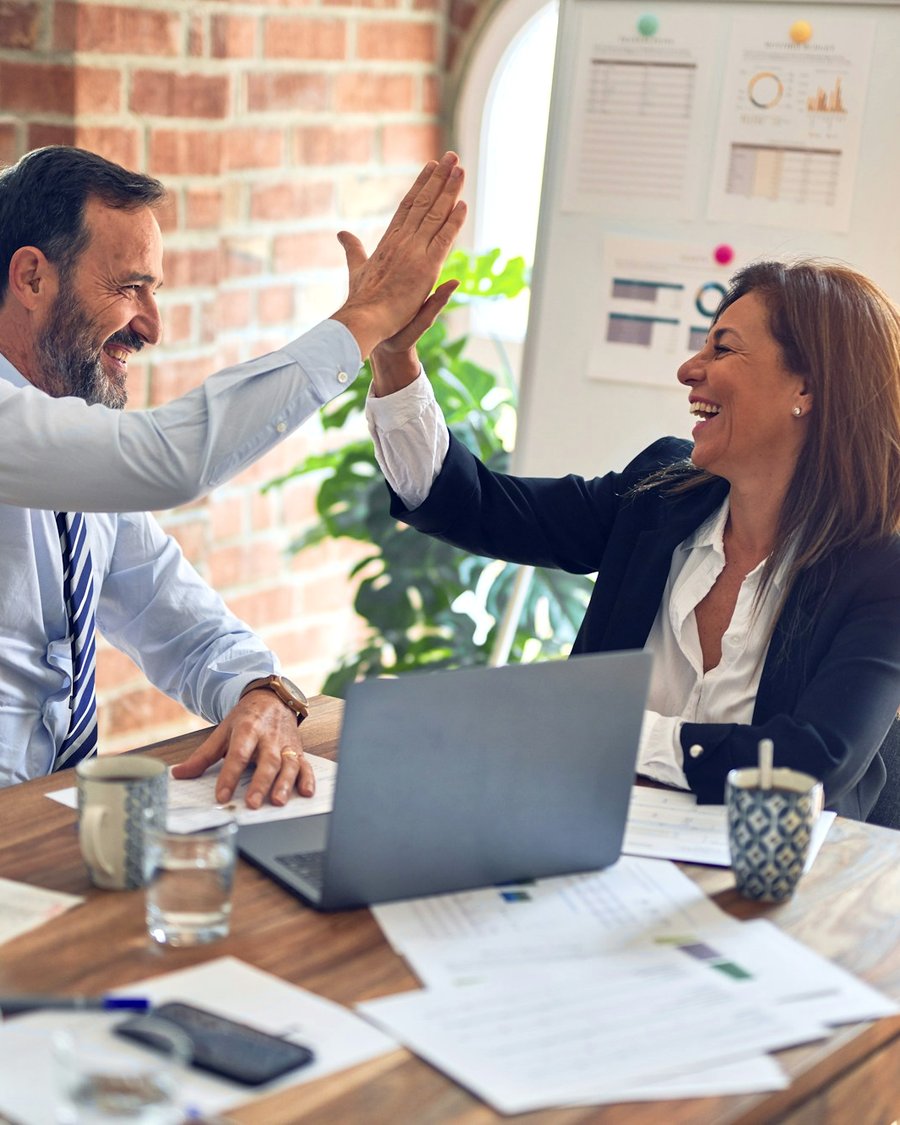 Colleagues sharing a high five at a meeting table