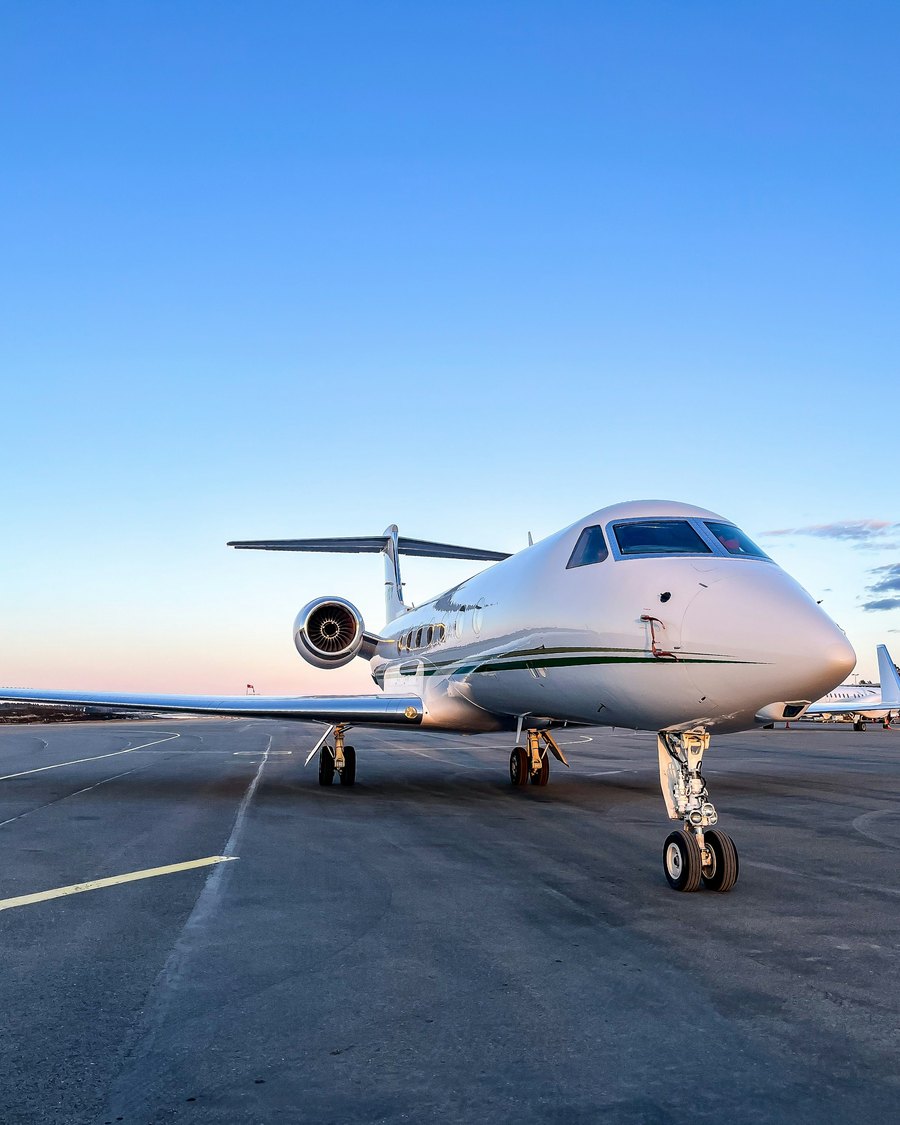 A white private jet on the tarmac at dusk