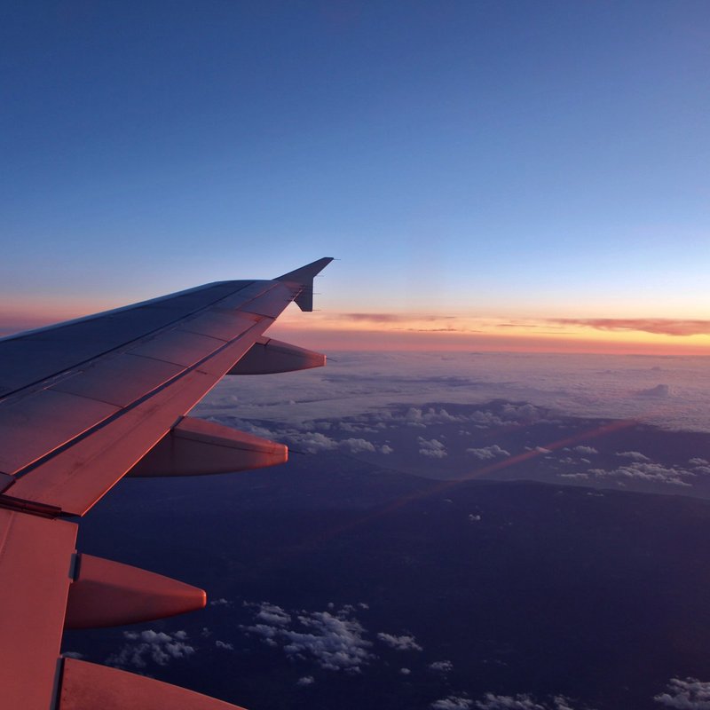 An airplane wing above the clouds at sunset
